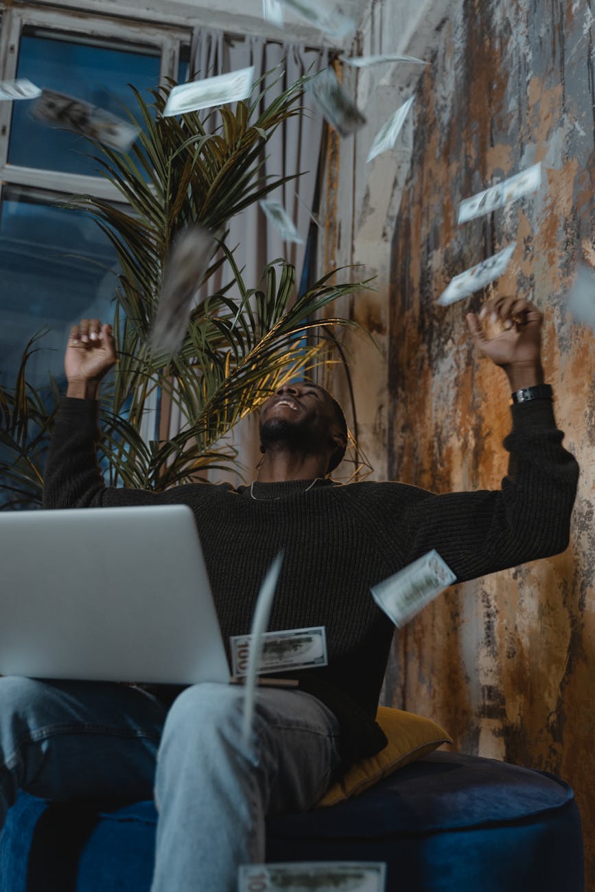 a man in a sweater celebrating with money in the air