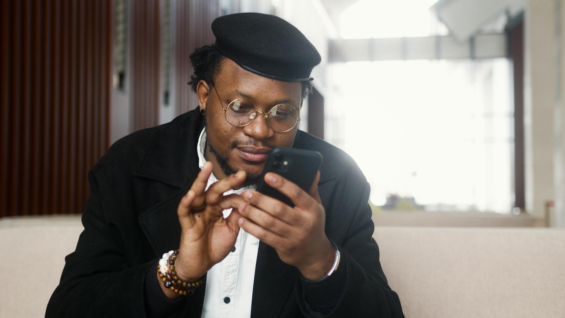 man in black suit jacket holding black smartphone