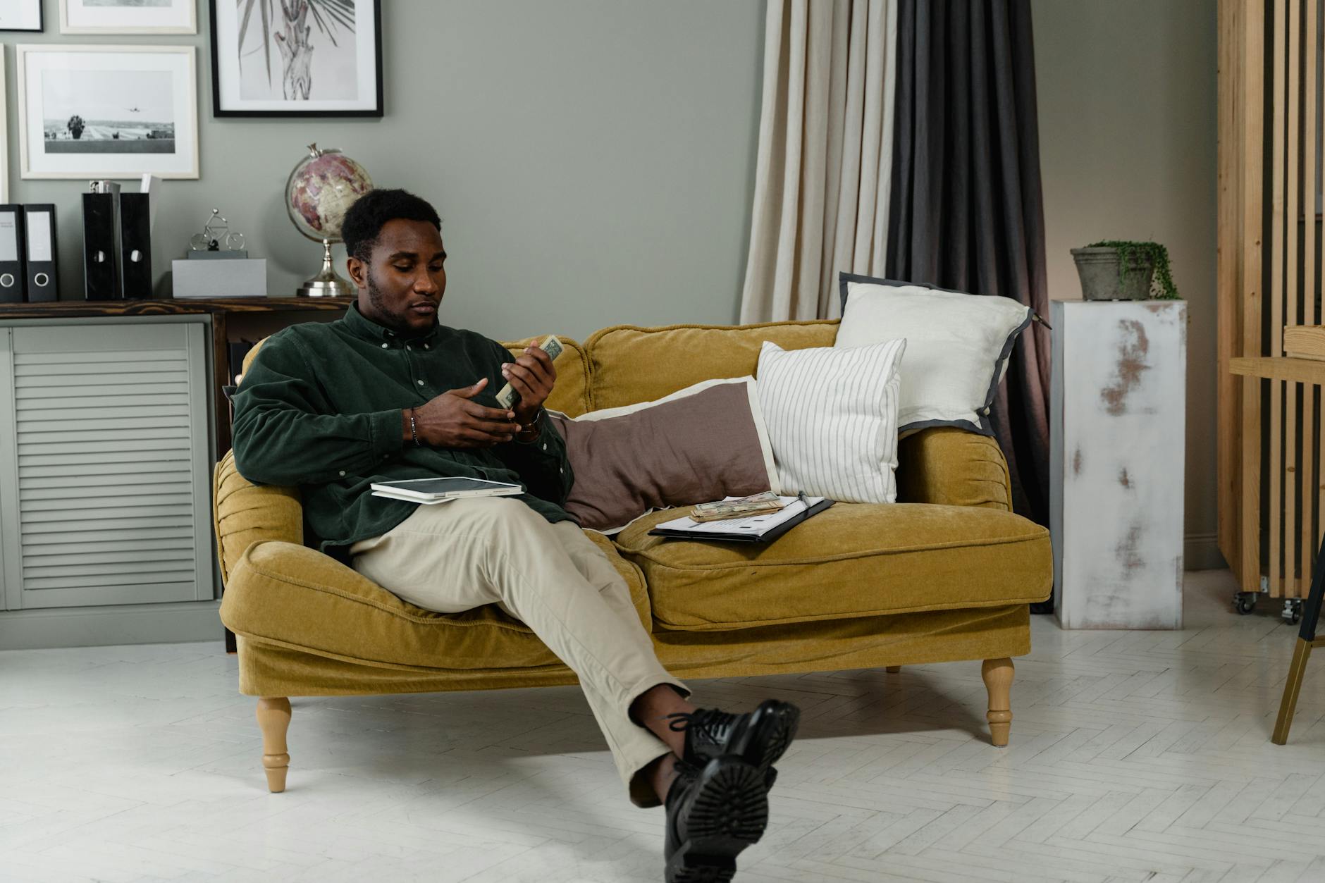 a woman in black long sleeves sitting on the couch while holding cash