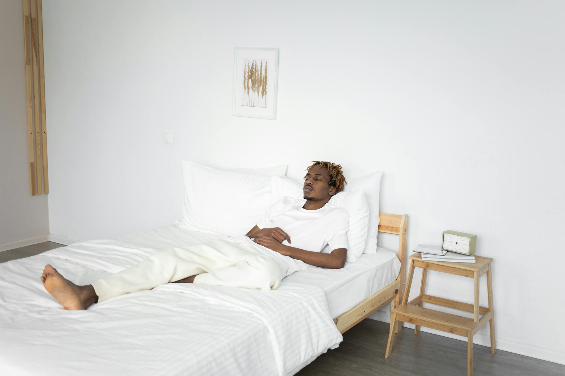 a man in white shirt sleeping on the bed