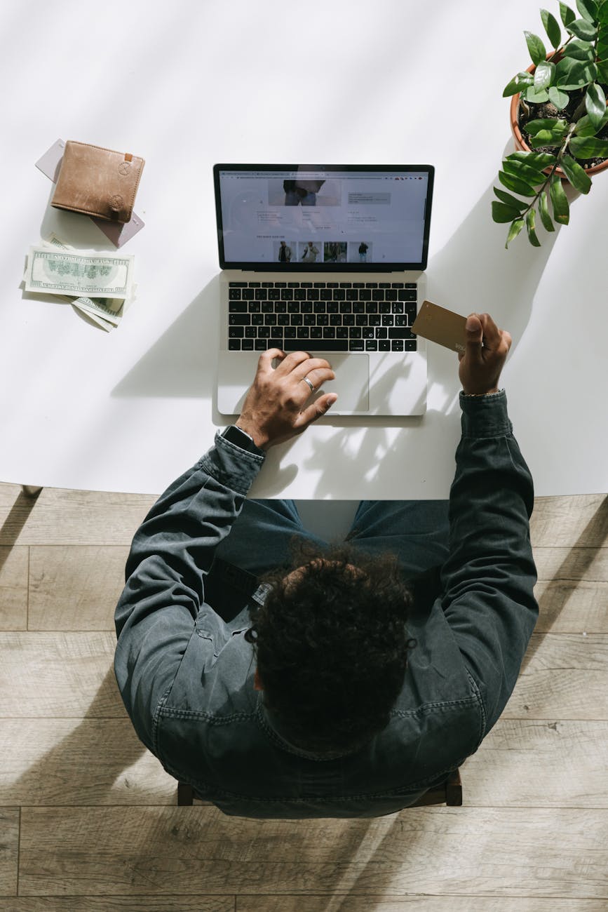 man using laptop while holding card