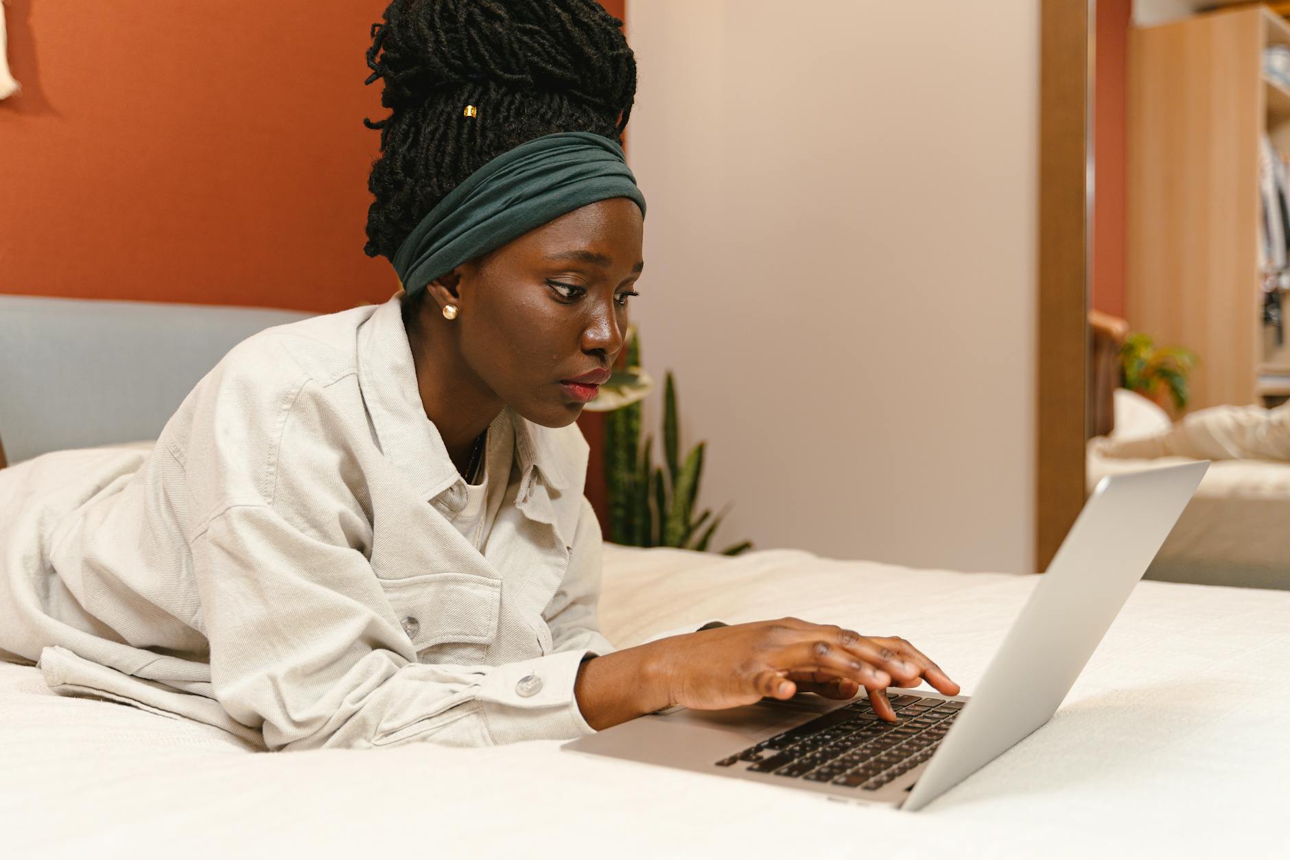 woman lying on bed using laptop