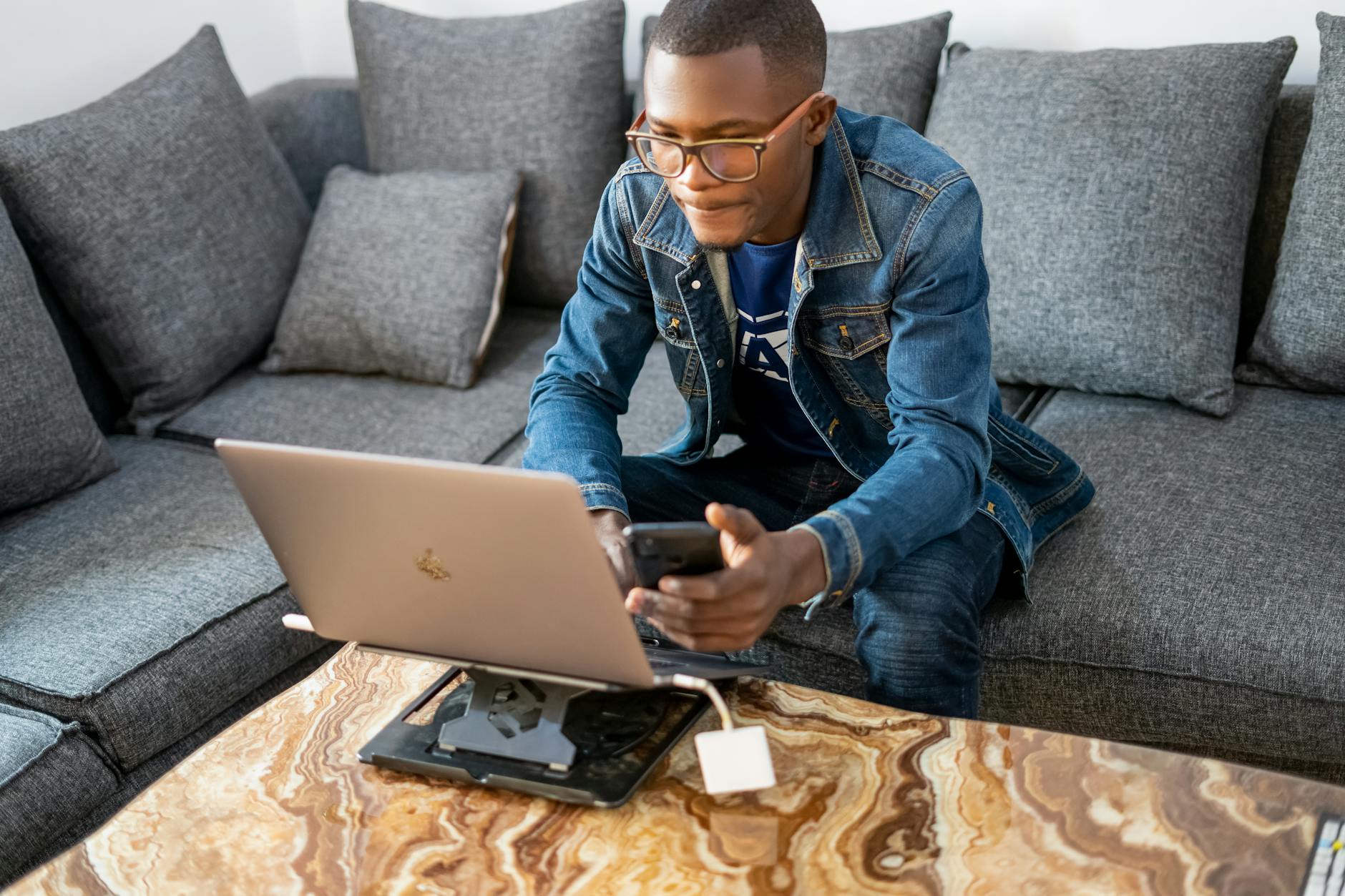 a man holding a smartphone while using a laptop